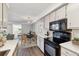 Well-lit kitchen with black appliances, white cabinets, and access to the adjacent living and dining areas at 1820 Newland Ct # 210, Lakewood, CO 80214