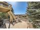 Backyard deck with stairs leading down to a stone paver path and landscaping at 7009 Winter Ridge Pl, Castle Pines, CO 80108