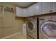 Efficient laundry room with front-loading washer and dryer, and white upper cabinets for storage at 25994 E Peakview Pl, Aurora, CO 80016