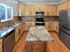 Open kitchen boasts stainless steel appliances, wooden cabinetry, granite counters, and hardwood floors at 19512 E 58Th Dr, Aurora, CO 80019