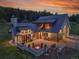 Stunning home showcasing an outdoor fire pit, a patio, and a lush tree-lined yard with amazing architecture at sunset at 5166 Bear Mountain Dr, Evergreen, CO 80439