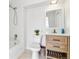 Bright bathroom featuring a shower-tub combo and modern wood vanity with storage, complemented by neutral tile flooring at 7158 W Roxbury Ave, Littleton, CO 80128