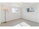 Bright basement bedroom with two windows and neutral carpeting, illuminated by a modern multi-light floor lamp at 7158 W Roxbury Ave, Littleton, CO 80128