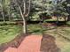 Landscaped backyard with mature trees, green lawn, mulch beds, and brick steps and walkways at 3975 S Cherry St, Cherry Hills Village, CO 80113