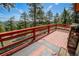 Wide deck offering views of the surrounding forest, framed by red wood railings at 8624 S Doubleheader Ranch Rd, Morrison, CO 80465