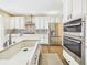 Bright kitchen features stainless steel appliances, white cabinetry, an island with a sink, and hardwood floors at 784 Sweet Pine Ct, Monument, CO 80132