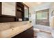 Modern bathroom with dual vanity, mosaic tile backsplash, and shower/tub combo with glass enclosure at 10957 Bryant St, Westminster, CO 80234