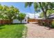 Fenced backyard with lush lawn, trees, and gravel space, complemented by a detached garage at 4197 S Grant St, Englewood, CO 80113