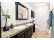 Bright bathroom featuring a double sink vanity with granite countertops and dark wood cabinets and trim at 4197 S Grant St, Englewood, CO 80113