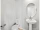Chic half bathroom featuring a pedestal sink, toilet, and a decorative mirror creating a fresh and inviting space at 14451 Pansy Loop, Morrison, CO 80465