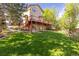 Expansive backyard with lush green lawn, mature trees, and a spacious deck at 2043 Fendlebrush St, Highlands Ranch, CO 80129