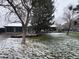 Charming single-story home featuring a well-manicured lawn and a three car garage, partially covered in snow at 8659 E Kenyon Ave, Denver, CO 80237