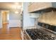 Close-up view of a gourmet kitchen gas range with stainless steel appliances and custom range hood at 8659 E Kenyon Ave, Denver, CO 80237