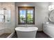 A luxurious bathroom featuring a freestanding tub under a window, with a marble shower and vanity at 8246 Raphael Ln, Littleton, CO 80125