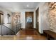 Elegant foyer with hardwood floors, wooden front door, stone accent wall, and staircase at 8246 Raphael Ln, Littleton, CO 80125