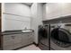 A modern laundry room with front-load washer and dryer, ample cabinetry, and countertop space at 8246 Raphael Ln, Littleton, CO 80125