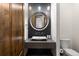 A stylish powder room featuring a unique vessel sink, round mirror, and modern fixtures at 8246 Raphael Ln, Littleton, CO 80125