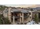 Stunning rear exterior view of a multi-level home, featuring stone accents and expansive deck overlooking scenic mountain landscape at 8246 Raphael Ln, Littleton, CO 80125