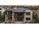 Impressive rear exterior showcasing a multi-story home with a stone facade, tiled roof, and outdoor living spaces at 8246 Raphael Ln, Littleton, CO 80125
