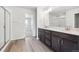 Bright bathroom with double sink, dark wood vanity, walk-in shower and laminate flooring at 1312 Sienna Peak Cir, Erie, CO 80516