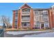 Three-story apartment complex exterior showcasing gray siding, red brick accents, and manicured landscaping at 14251 E 1St Dr # 308, Aurora, CO 80011