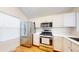 Modern kitchen with stainless steel appliances, white cabinets, and hardwood floors at 11836 Columbine St, Thornton, CO 80233