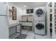 Well-lit laundry room with stackable washer/dryer and black and white patterned floors at 4891 Depew St, Denver, CO 80212