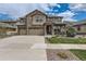 Charming two-story home with a stone and siding exterior, well-manicured lawn, and a three car garage at 8133 Arapahoe Peak St, Littleton, CO 80125