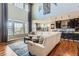 Open-concept living room with two story windows, a large sectional sofa, and access to the kitchen and dining areas at 8133 Arapahoe Peak St, Littleton, CO 80125