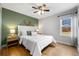 Bedroom features green accent wall, hardwood flooring, ceiling fan, and natural light from window at 1876 S Adams St, Denver, CO 80210