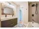 Modern bathroom featuring a tiled shower, patterned floors, and a sleek vanity with a rustic mirror at 6935 W 16Th Ave, Lakewood, CO 80214