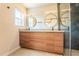 Modern bathroom featuring a double vanity with wood cabinets, round mirrors, and a glass-enclosed shower at 6935 W 16Th Ave, Lakewood, CO 80214