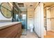 Modern bathroom with wood vanity, dual mirrors, a glass-enclosed shower, and a barn door to closet at 6935 W 16Th Ave, Lakewood, CO 80214