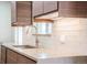 Modern kitchen featuring wood cabinets, a stainless steel faucet, and a light-colored countertop and backsplash at 6935 W 16Th Ave, Lakewood, CO 80214