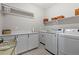 Well-organized laundry room with modern washer and dryer, ample counter space, and overhead storage shelves at 5035 Old Ranch Dr, Longmont, CO 80503