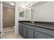 A bathroom with gray cabinets, dark granite counters, a shower, and multiple mirrors at 2026 S Pitkin St, Aurora, CO 80013