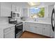 Well-lit kitchen featuring stainless steel appliances, white cabinets, and wood flooring at 1248 W 135Th Ave, Denver, CO 80234