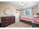 Cozy bedroom with a large window, dresser, round decorative mirror, and light colored carpet at 8533 S Flower Ct, Littleton, CO 80128