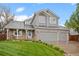 Charming gray two-story home with a three-car garage and lush green lawn at 8533 S Flower Ct, Littleton, CO 80128
