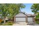 Exterior view of a well-maintained home with a three-car garage, brick accents, and a manicured front lawn at 9638 Marion Way, Thornton, CO 80229
