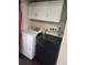 Convenient laundry area with a modern white dryer, black washer, wooden-like floor and white cabinets above appliances at 185 S Sable Blvd # T18, Aurora, CO 80012