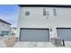 View of the home's gray two-car garage with number, air conditioner, and street view at 18938 E 64Th Pl, Denver, CO 80249