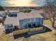 Aerial view of a blue townhome with fenced yard and nearby trees at sunset with mountains in distance at 7946 Chase Cir # 112, Arvada, CO 80003