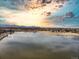 Scenic aerial view of a lake, park, and distant mountains under a vibrant sunset sky at 7946 Chase Cir # 112, Arvada, CO 80003