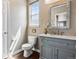 Bathroom with a gray vanity, decorative mirror, toilet, and window allowing natural light to illuminate the space at 2794 Lima St, Denver, CO 80238