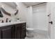 Bathroom with dark wood vanity, decorative mirror, and tub with white tiled walls at 211 Luna Ct, Erie, CO 80516