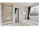 Bathroom featuring a glass enclosed shower, soaking tub, and window with dark curtains at 9957 Candlewood Ln, Highlands Ranch, CO 80126
