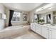 Bright bathroom featuring a soaking tub with tile surround and dual sinks with white cabinets at 9957 Candlewood Ln, Highlands Ranch, CO 80126