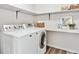 Bright laundry room with washer, dryer, shelving, and modern decor at 9957 Candlewood Ln, Highlands Ranch, CO 80126