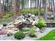 Multi-tiered rock waterfall feature with mature landscaping and a bench seat nearby at 878 Tree Bark Ter, Colorado Springs, CO 80132